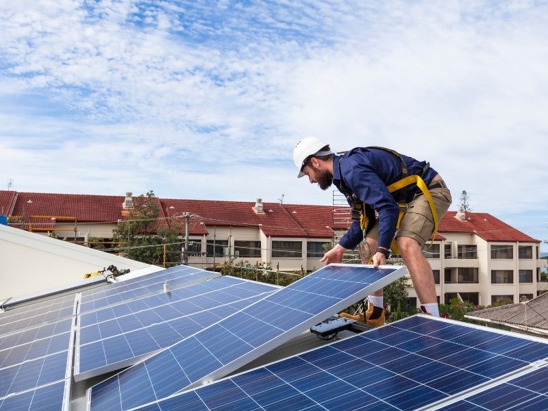 Técnico especialista instalando painel de energia solar em telhado residencial.